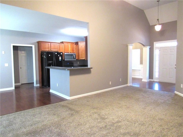 kitchen with black fridge with ice dispenser, stainless steel microwave, brown cabinets, decorative light fixtures, and dark colored carpet