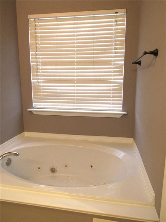 bathroom featuring plenty of natural light and a tub with jets