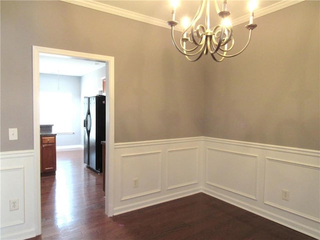 unfurnished dining area with a wainscoted wall, crown molding, a chandelier, and dark wood-style flooring