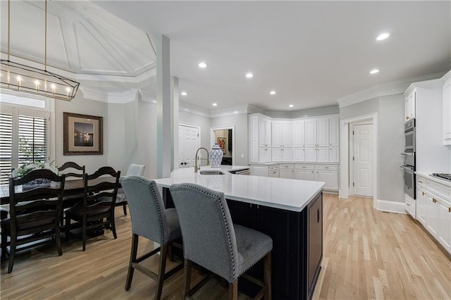 1021 Wetherby Way, Johns Creek, GA 30022 - kitchen with a sink, crown molding, white cabinetry, light wood-style floors, and a spacious island
