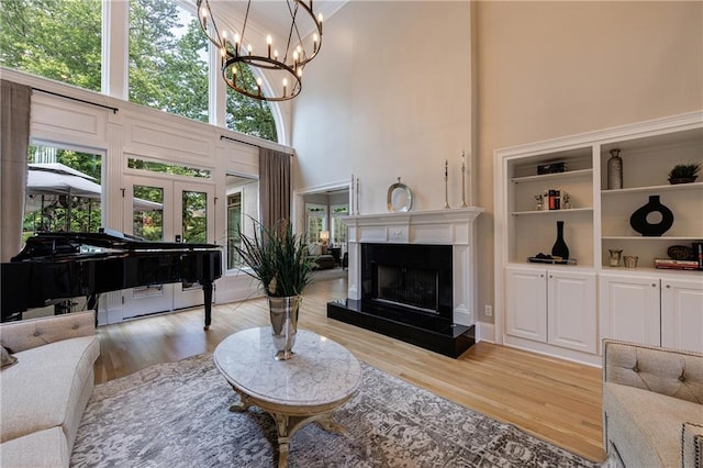 1021 Wetherby Way, Johns Creek, GA 30022 - living room with wood finished floors, a chandelier, a high ceiling, a tile fireplace, and french doors