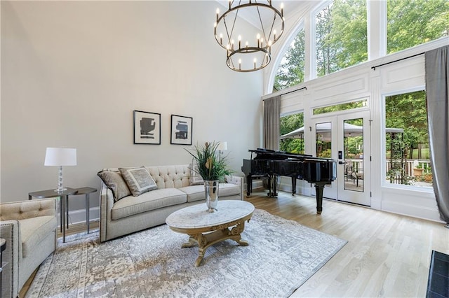 1021 Wetherby Way, Johns Creek, GA 30022 - living room featuring a chandelier, wood finished floors, a towering ceiling, french doors, and baseboards