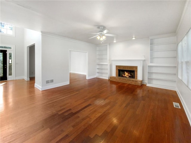 unfurnished living room with ornamental molding, a fireplace, built in features, ceiling fan, and wood-type flooring