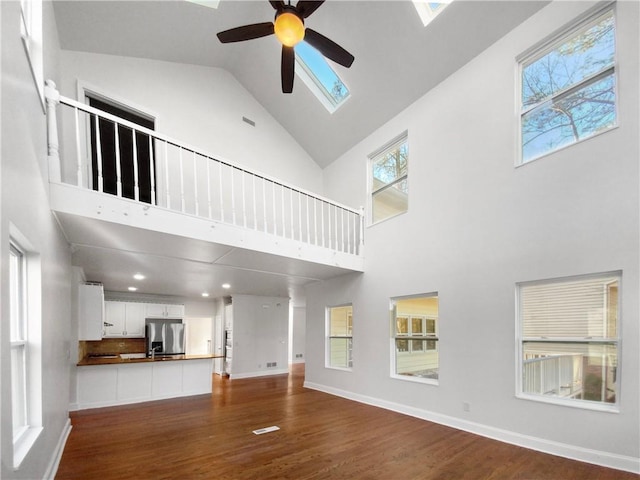 unfurnished living room with high vaulted ceiling, wood-type flooring, and ceiling fan