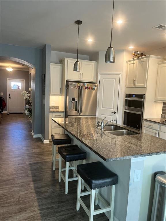 kitchen featuring a kitchen breakfast bar, stainless steel appliances, sink, a center island with sink, and white cabinets