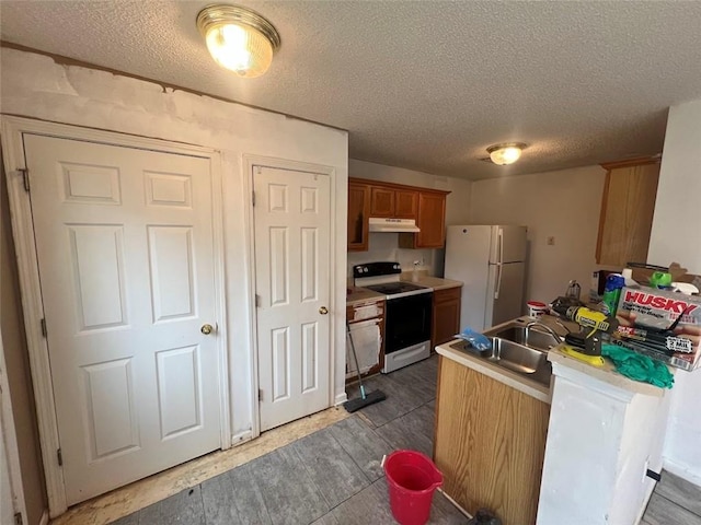 kitchen featuring sink, white appliances, and a textured ceiling