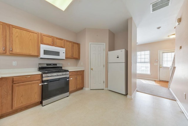 kitchen with white appliances, baseboards, visible vents, and light countertops