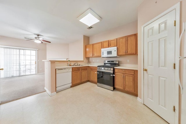 kitchen featuring light countertops, visible vents, a sink, white appliances, and a peninsula