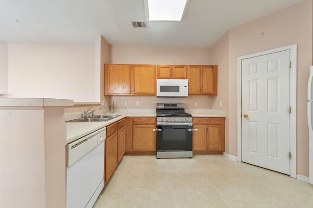 kitchen with white appliances, a sink, visible vents, baseboards, and light countertops