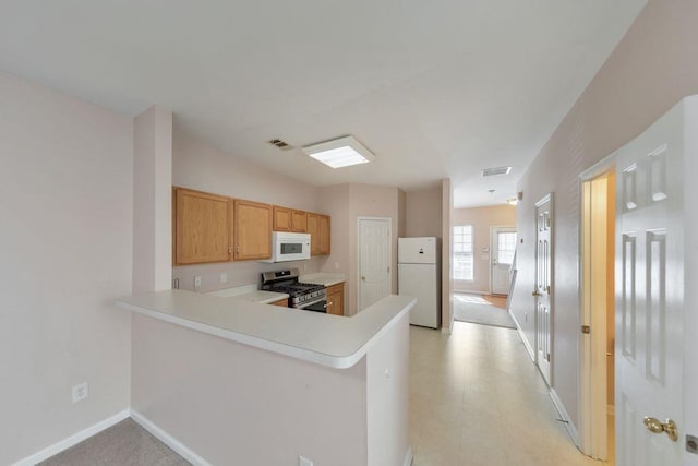 kitchen with white appliances, baseboards, visible vents, a peninsula, and light countertops