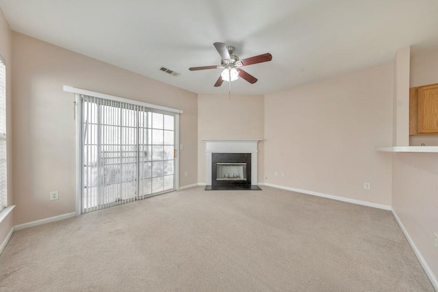 unfurnished living room featuring baseboards, a fireplace, visible vents, and light colored carpet