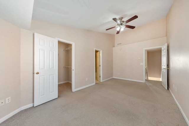 unfurnished bedroom with lofted ceiling, a spacious closet, and baseboards