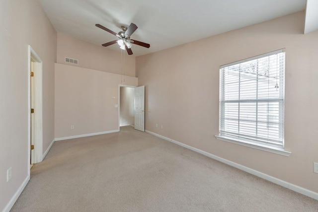 unfurnished room featuring light colored carpet, visible vents, ceiling fan, and baseboards