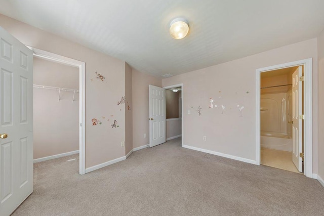 unfurnished bedroom featuring a closet, light colored carpet, a spacious closet, and baseboards