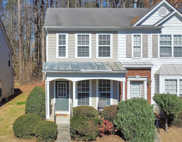 townhome / multi-family property with metal roof, brick siding, a standing seam roof, and a porch