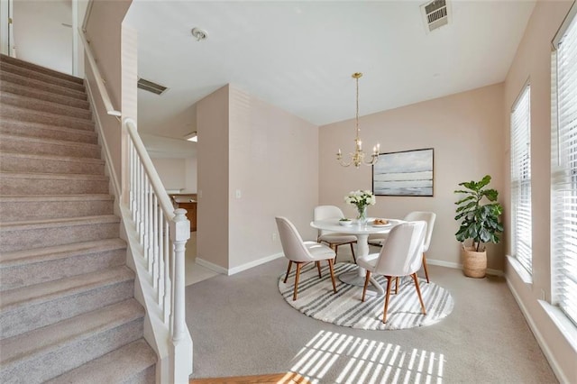 carpeted dining room with a chandelier, stairway, visible vents, and baseboards