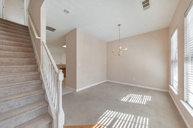 staircase featuring visible vents, carpet, a wealth of natural light, and an inviting chandelier