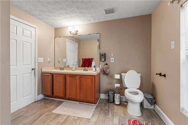 bathroom with toilet, vanity, a textured ceiling, and hardwood / wood-style flooring