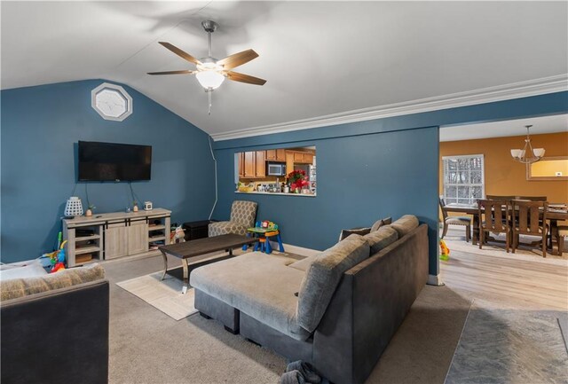 living room featuring lofted ceiling, ceiling fan with notable chandelier, and ornamental molding