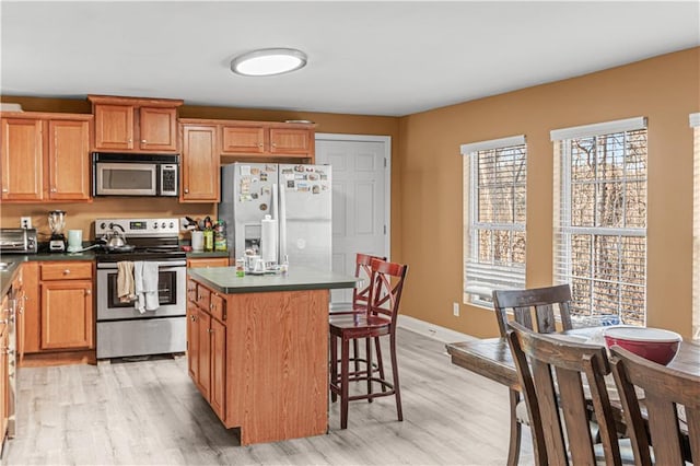 kitchen with a kitchen island, light wood-type flooring, stainless steel appliances, and a breakfast bar area