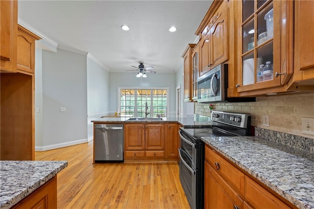 387 Lauren Marie Dr, Braselton, GA 30517 - kitchen featuring appliances with stainless steel finishes, a sink, brown cabinetry, light wood-style floors, and a ceiling fan