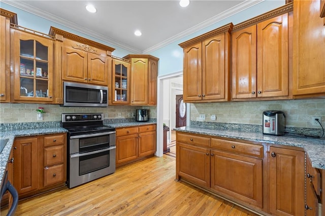 387 Lauren Marie Dr, Braselton, GA 30517 - kitchen featuring appliances with stainless steel finishes, brown cabinetry, light wood-style flooring, light stone countertops, and ornamental molding