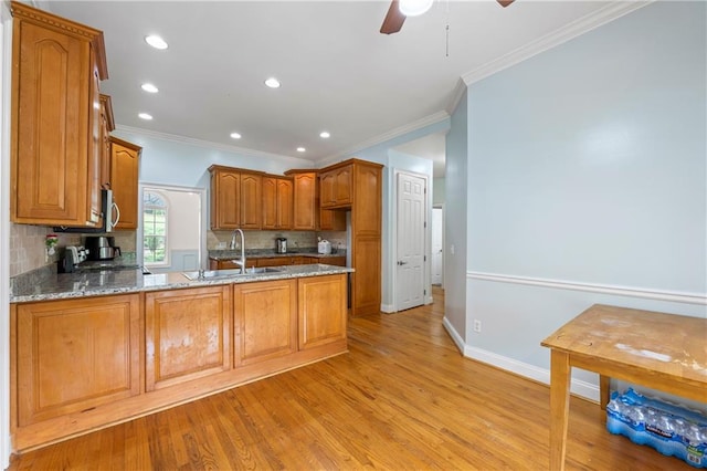 387 Lauren Marie Dr, Braselton, GA 30517 - kitchen featuring a sink, tasteful backsplash, light wood-style floors, ornamental molding, and brown cabinetry