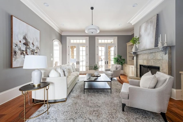 living room with baseboards, ornamental molding, french doors, a fireplace, and wood finished floors