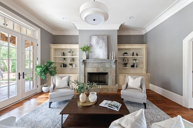 living room with french doors, wood finished floors, ornamental molding, and a tile fireplace