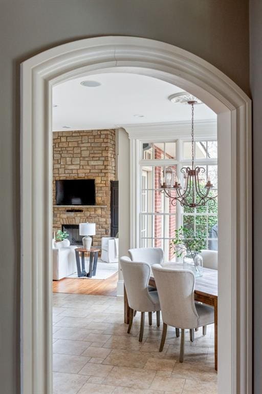 dining space featuring a stone fireplace, stone finish floor, and an inviting chandelier