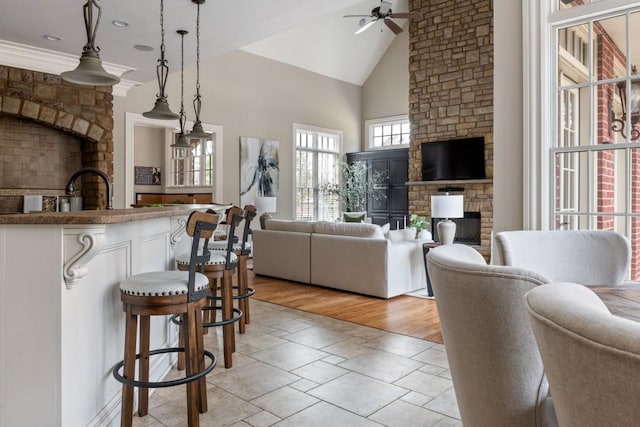 living area featuring a ceiling fan, high vaulted ceiling, and a fireplace