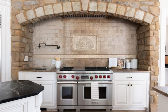 kitchen with decorative backsplash, dark countertops, double oven range, and white cabinetry