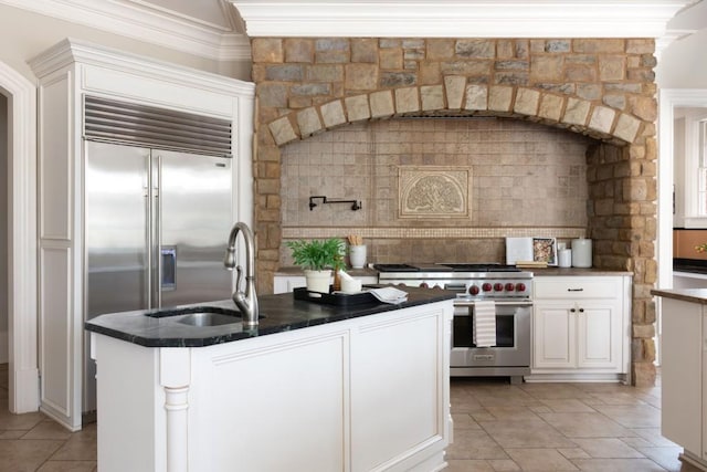 kitchen featuring a sink, tasteful backsplash, high end appliances, and white cabinetry