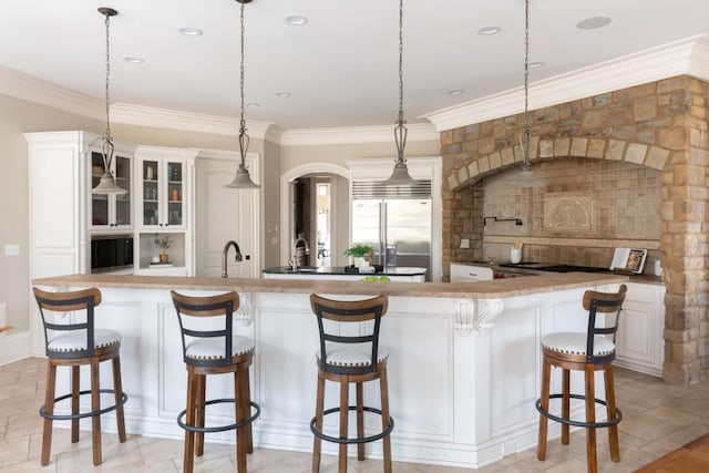 kitchen featuring a spacious island, a breakfast bar area, crown molding, and built in fridge