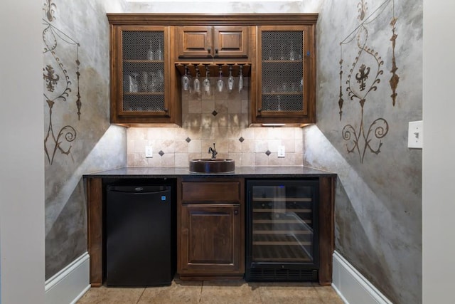 bar with indoor wet bar, backsplash, refrigerator, and beverage cooler