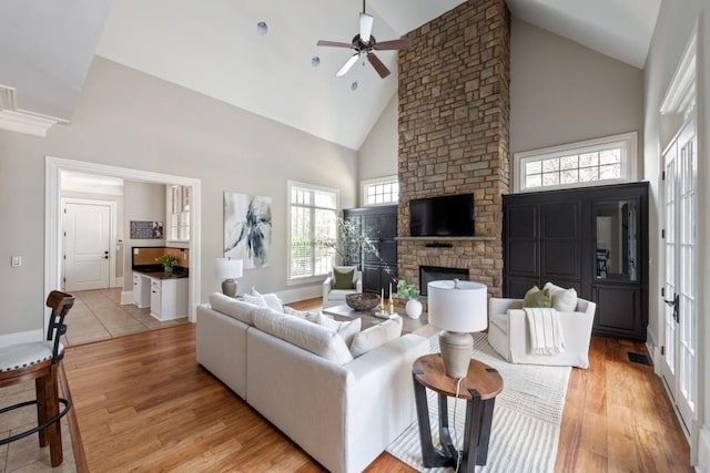 living room featuring visible vents, high vaulted ceiling, light wood-style flooring, and a fireplace