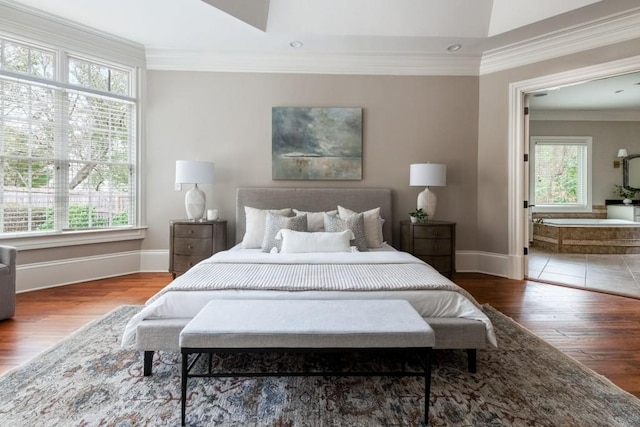 bedroom featuring connected bathroom, baseboards, wood finished floors, and crown molding