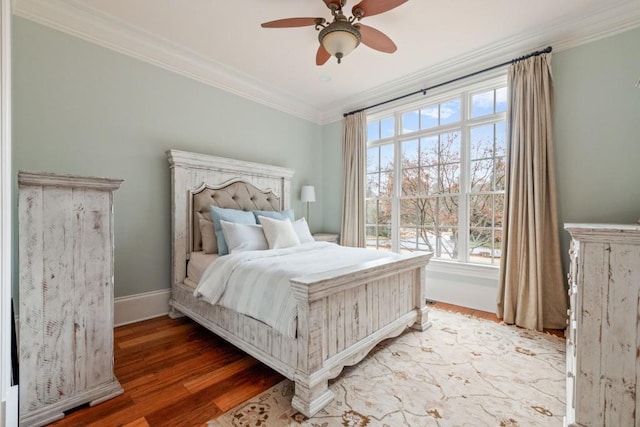 bedroom with a ceiling fan, crown molding, baseboards, and wood finished floors