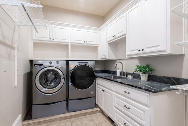 laundry area with cabinet space, light tile patterned floors, washer and dryer, and a sink