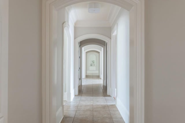 corridor with arched walkways, light tile patterned flooring, and ornamental molding