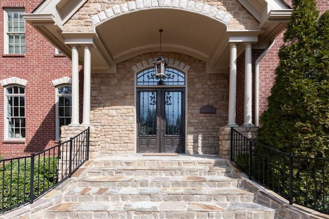 entrance to property featuring french doors, stone siding, and brick siding