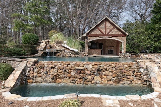 view of pool with an outdoor brick fireplace