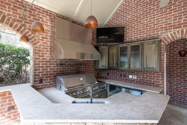 kitchen with brick wall, vaulted ceiling, glass insert cabinets, concrete flooring, and wall chimney range hood