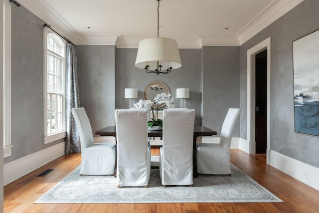 dining area featuring visible vents, ornamental molding, baseboards, and wood finished floors