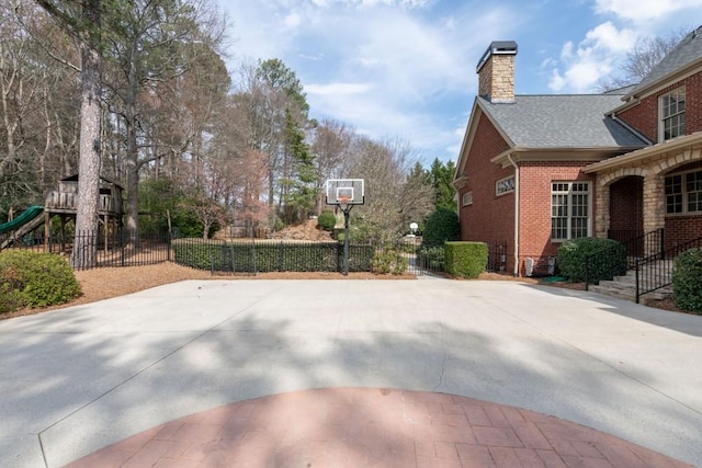 view of basketball court featuring a playground and fence