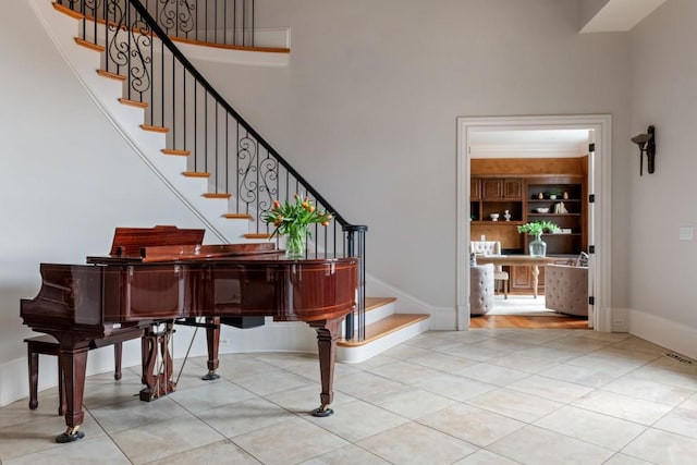 tiled foyer entrance featuring baseboards, stairs, and a towering ceiling