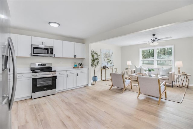 kitchen featuring stainless steel appliances, white cabinetry, ceiling fan, and light hardwood / wood-style floors