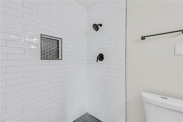 bathroom with a tile shower and toilet