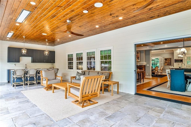 living area with stone tile flooring, a healthy amount of sunlight, and ceiling fan
