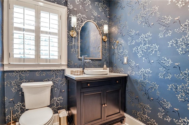 bathroom with toilet, a healthy amount of sunlight, vanity, and baseboards